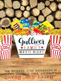 three small buckets filled with popcorn sitting on top of a wooden table next to logs