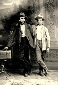 two men standing next to each other in front of a painting