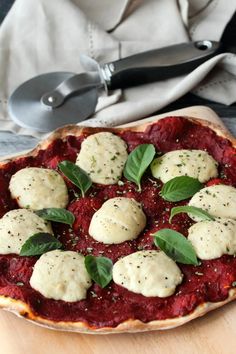 a pizza topped with mozzarella and basil on top of a wooden cutting board