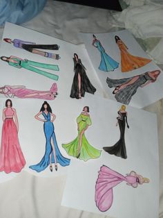 four paper drawings of women in evening gowns and dress shoes on top of a bed