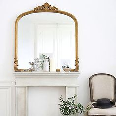 a white fireplace with a mirror and some books on the mantle in front of it