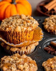 muffins in a muffin tin with cinnamon and an orange pumpkin behind them