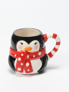 a black and white penguin mug with a red scarf around it's neck, on a white background