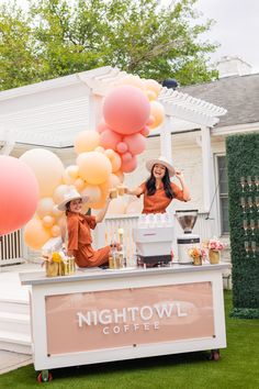 two women standing behind a coffee cart with balloons