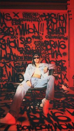 a woman sitting on top of a chair in front of graffiti