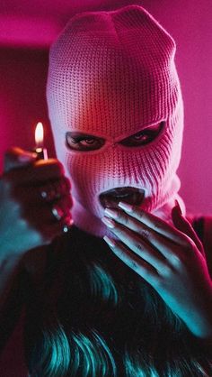 a woman in a white mask holding a lit candle