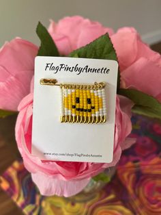 a yellow beaded brooch sitting on top of a pink carnation flower bouquet