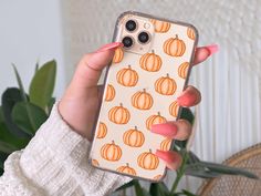 a woman holding up her phone case with pumpkins on it