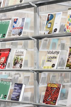 several stacks of books are stacked on each other in front of a wall with clear plastic bins