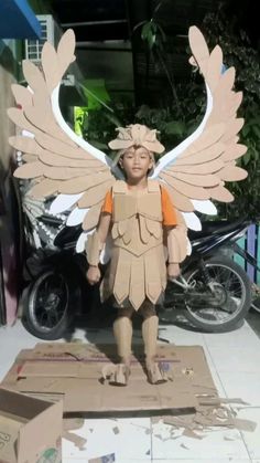 a cardboard angel statue sitting on top of a box next to a motorbike