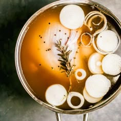 a pot filled with liquid and onions on top of a table