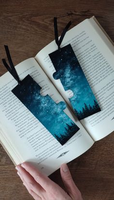 an open book with two pieces of paper cut out to look like trees and the sky