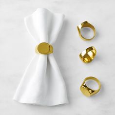 gold napkin rings, napkin ring and napkin holder on top of a white tablecloth