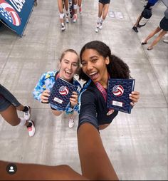 two girls are holding up their medals in the middle of a group of other people