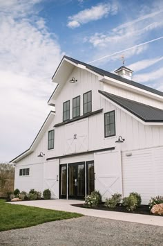 a large white barn sitting on top of a lush green field