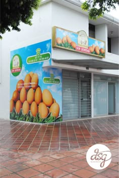 an advertisement on the side of a building with oranges for sale in front of it