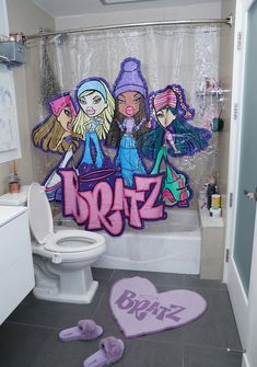 a bathroom decorated with cartoon characters on the shower curtain and rugs, along with slippers