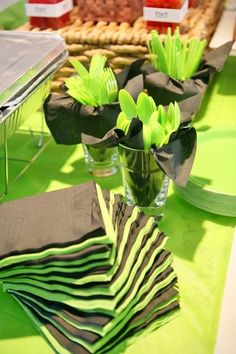 a table topped with green napkins and vase filled with flowers