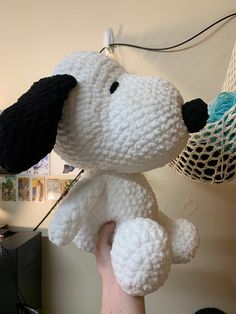 a hand holding a white stuffed dog with black ears