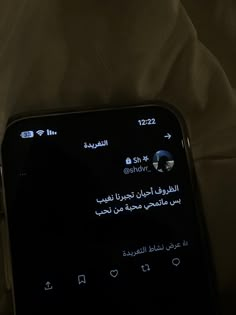 a cell phone sitting on top of a bed next to a white sheet with arabic writing