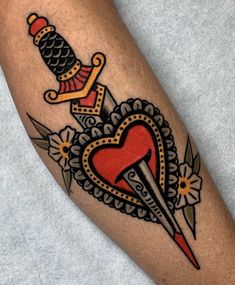 a tattoo on the leg of a person with a heart and dagger in it's center