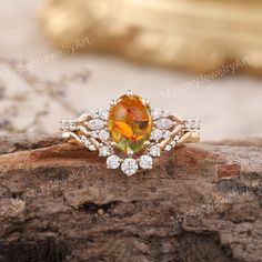 an orange and white diamond ring sitting on top of a piece of wood