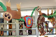 several paper animals hanging from the ceiling in a classroom with pictures on the wall behind them