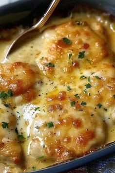 a close up of food in a pan with a spoon on the side that has cheese gravy and parsley