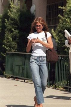 a woman walking down the street while looking at her cell phone