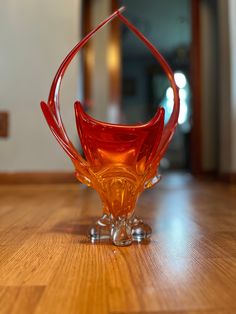 an orange glass vase sitting on top of a wooden table