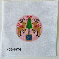 a cross stitch christmas card with two deers and a tree on the front side