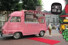 a pink ice cream truck parked in front of a building