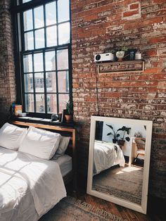 a bed sitting next to a large mirror in a bedroom