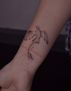 a person's arm with a small tattoo of a bird on the left wrist