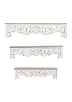 three white shelfs with ornate designs on them