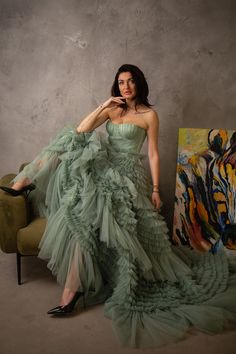 a woman in a green dress is sitting on a chair and posing for the camera