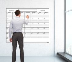 a man standing in front of a whiteboard with several times on it and pointing to the wall