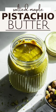 a jar filled with pistachio butter next to two spoons