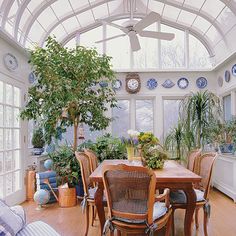 a dining room filled with lots of furniture and plants on top of wooden flooring