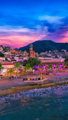 an aerial view of the beach and city at sunset with palm trees in the foreground