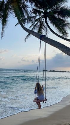 a woman sitting on a swing at the beach