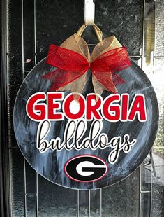 a sign that says georgia bulldogs hanging on a door with a red and gold bow