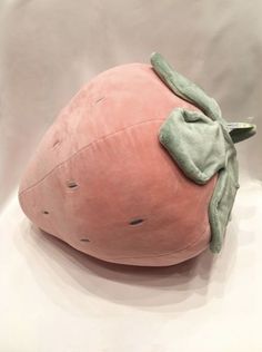 a pink pillow with a green bow on it's head sitting on a white surface