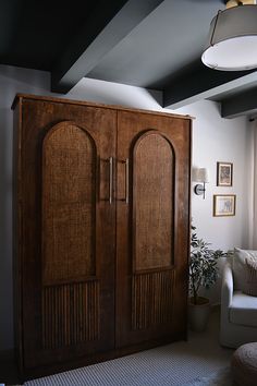 a large wooden cabinet sitting in the corner of a room next to a white couch