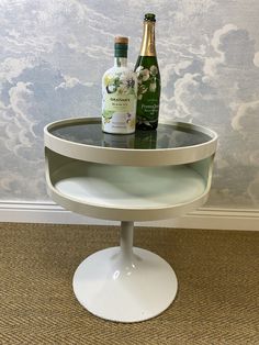 two bottles are sitting on top of a round table in front of a wallpapered wall