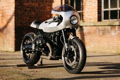 a silver motorcycle parked in front of a brick building