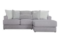 a gray sectional couch with pillows on the top and bottom cushions in front of it