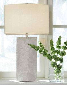 a table lamp sitting next to a vase with plants in it on a window sill