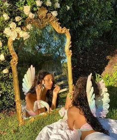 two women sitting on the grass in front of a mirror