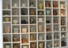 a white shelf filled with lots of different types of coffee mugs on top of it